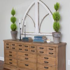 Master Bedroom Dresser With Potted Topiaries and Decorative Wall Hanging