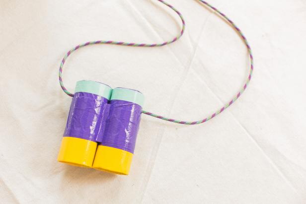 Cut cord, string or ribbon to around 28 inches. Thread each end of the cord through the holes of the binoculars. Create a small knot inside the binoculars at the ends, then trim excess cord (Image A & B).
