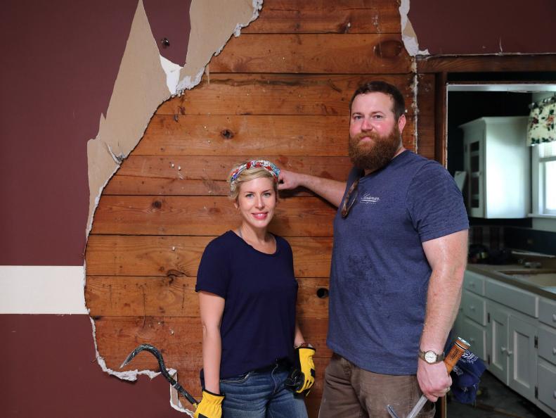 As seen on Home Town, Ben (R) and Erin Napier (L) work together to pull down the existing sheetrock from the dining room in the Hayes residence to create a larger opening between the dining room and kitchen. (demolition, portrait)