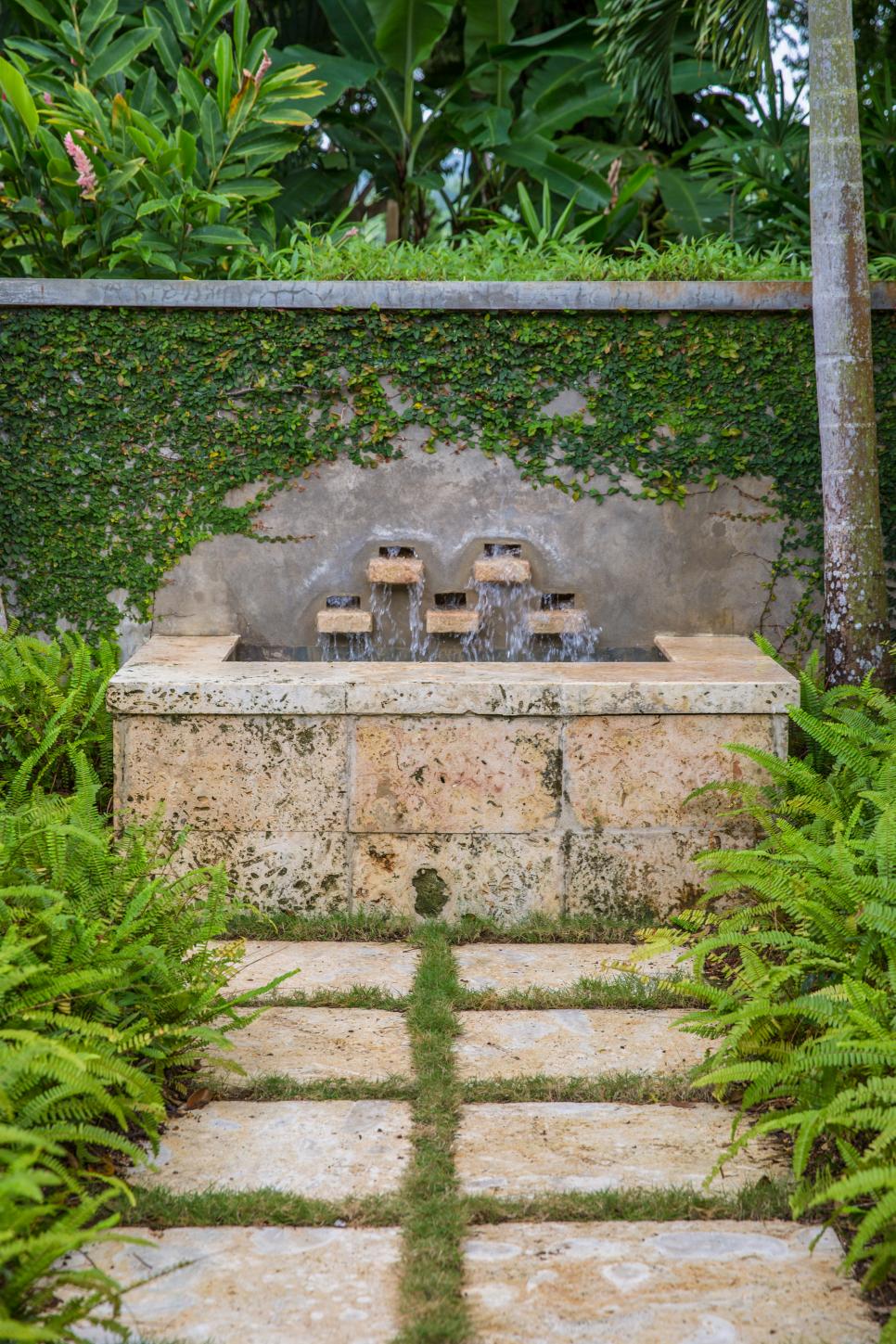 Water Fountain Tucked Into Garden tropical garden with weathered stone fountain