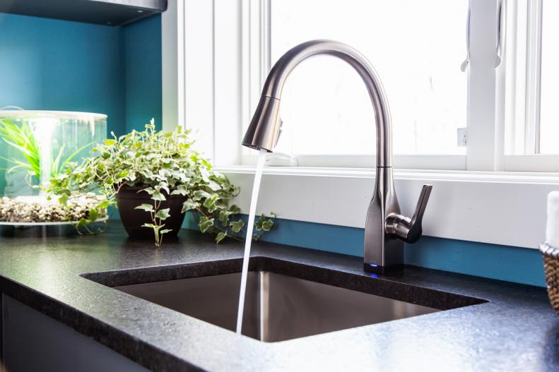 The laundry room’s undermount utility sink has a black stainless single handle pull-down faucet that requires just a simple touch to start or stop the flow of water. On the counter next to the sink sits a potted ivy plant and a beautiful LED aquarium tank that allows an unobstructed, 360-degree view of its mesmerizing underwater world.