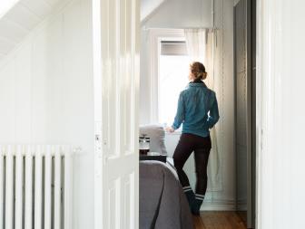 Woman Standing at the Window in Attic Apartment