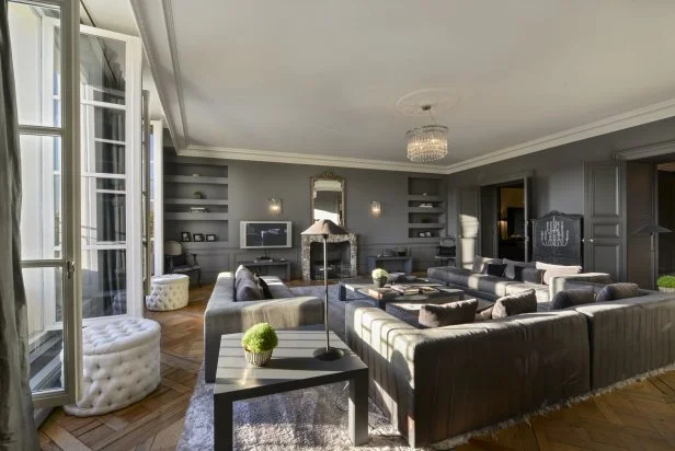 Oversized gray sofas provide plenty of comfy seating in this neutral contemporary living room. A long row of windows allow natural light to flood the space and perfect for entertaining.