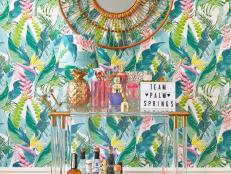 eclectic living room with floral wallpaper and lucite bar cart