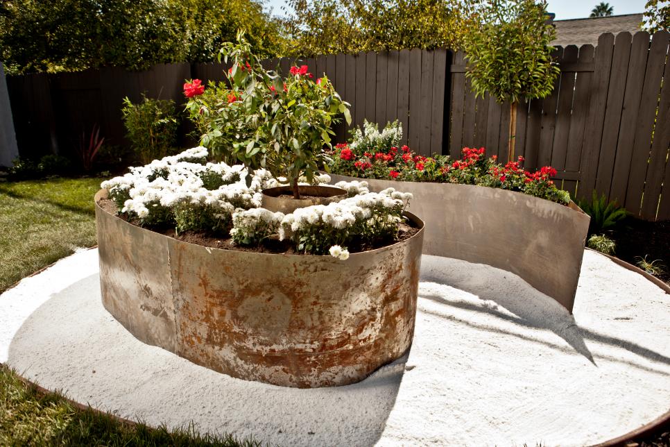Fenced Backyard With Oversized Metal Planters in White Gravel Large Distressed-Metal Planters in a Fenced Backyard