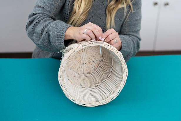 Thread needle with a long piece of twine, and weave through the top of the basket. Tie a knot to keep it secure. Add two tassels onto the needle at a time, and attach to the basket until you’re finished.