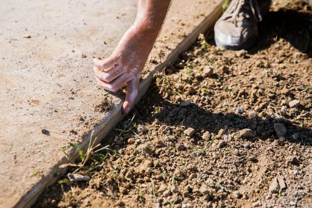 Rake soil level and ensure that it’s one inch below the grade of sprinkler heads or paved areas, like sidewalks, patios or driveways. Raking evens out the surface and also creates loose soil particles, which are ideal for grass roots to sink into.