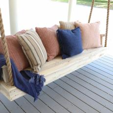 Wood Porch Swing Topped With Throw Pillows