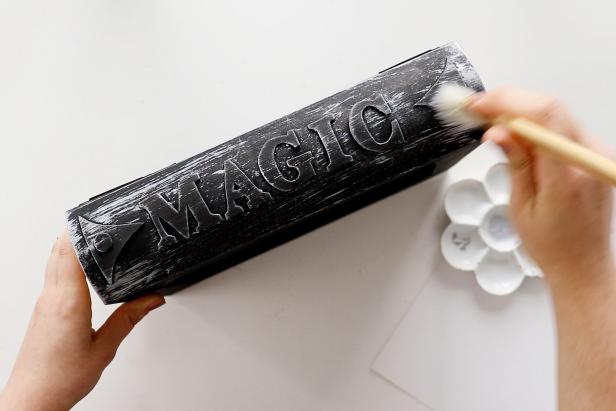 Next, sweep silver paint onto the spines of the black book boxes with a stiff brush to give them depth and an aged look.