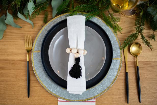 Place Setting With Napkin Ring With Tassel and Green Foliage in Background
