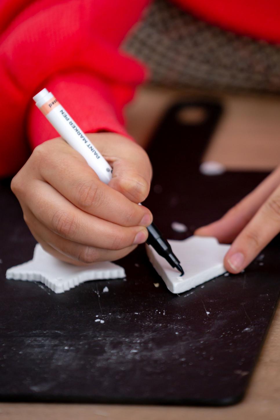 How to Make Salt Dough Christmas Ornaments Learn how to make salt dough for Christmas ornaments on HGTV.com.
Hands Decorating Dough Tree Ornament With Marker