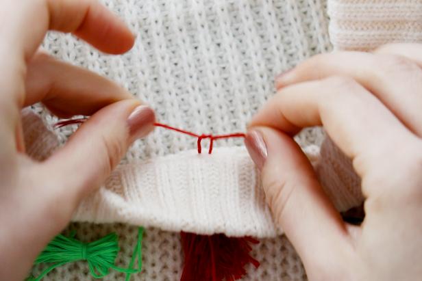 Embellish a plain white sweater with a red and green tassels to make a cute and festive sweater for the holidays.