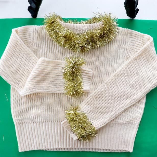 Embellish a plain white sweater with metallic tinsel to make a cute and festive sweater for the holidays.