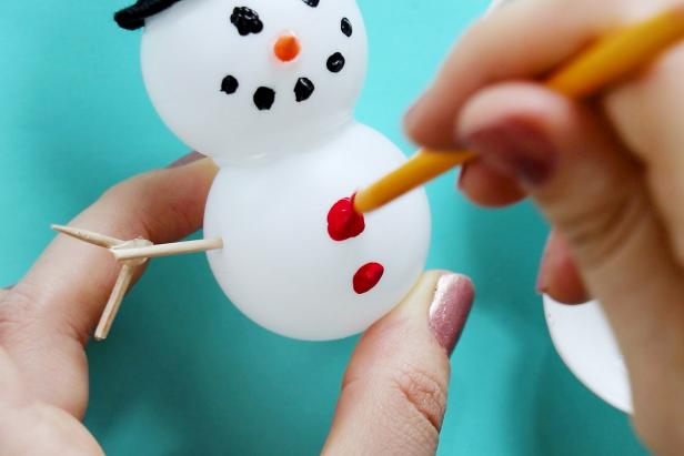 Finally, use the end of a paintbrush to dot on paint as the snowman’s eyes, mouth and buttons.
