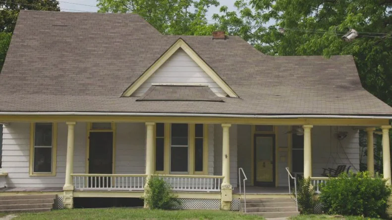 Bright yellow trim, double front doors and concrete stairs steal from the charm of this historic Bentonville home, as seen on the HGTV series Almost Home. BEFORE_9