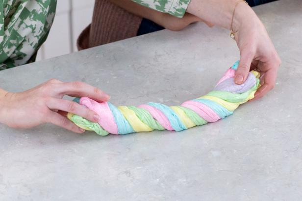 Two Hands Twisting Ropes of Different Color Slime Together to Make One