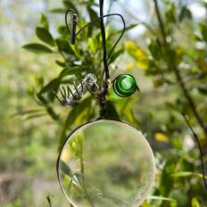 Upcycled Garden Art Made out of a Glass Lens, Wire and an Apothecary Bottle.