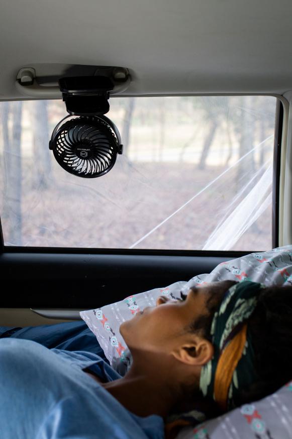 Girl sleeping in car under fan