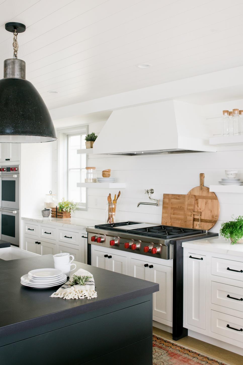 Modern Black-And-White Kitchen Black Pendant Light Hangs Above Kitchen Island In Modern Kitchen