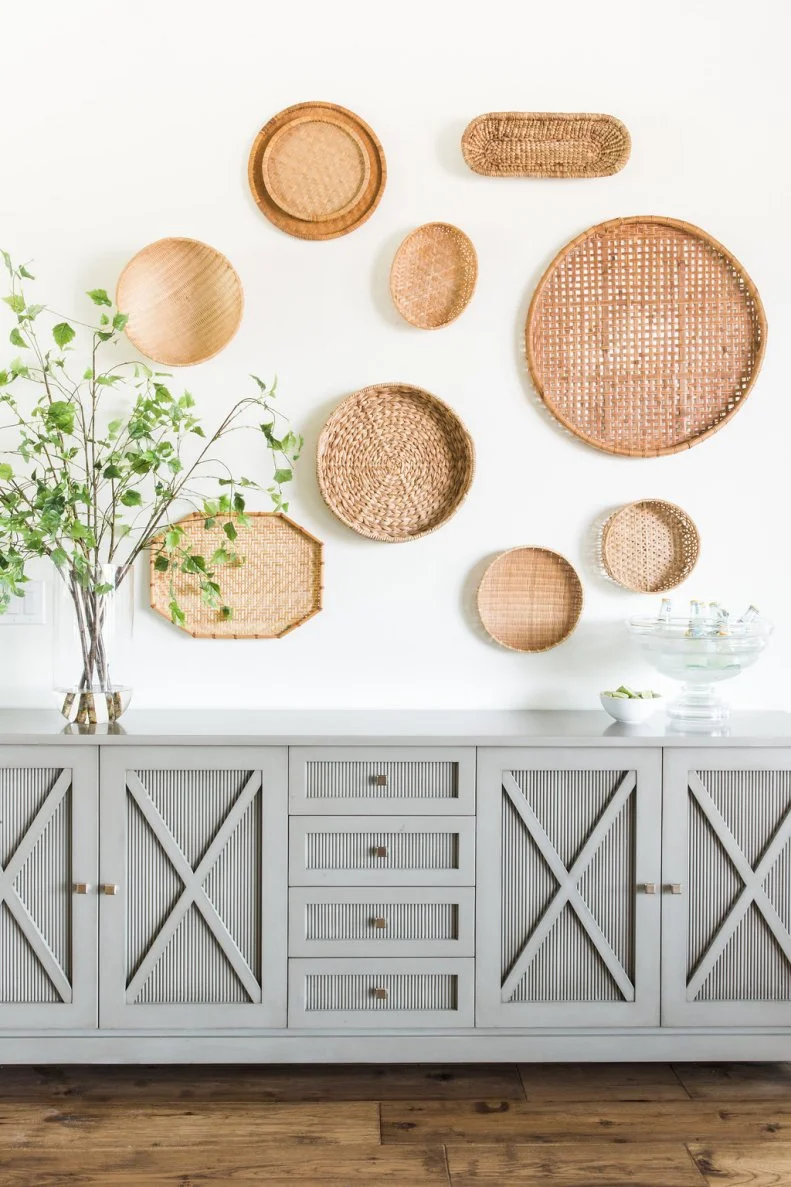 A Vase And Plant Sit On The Sideboard With Woven Baskets Hanging Above