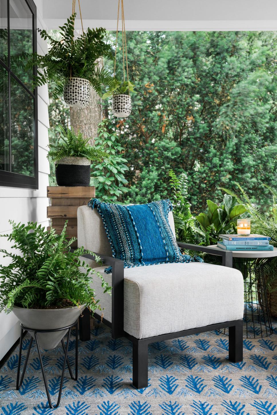 Layers of Blue and White Plants Surround Comfy Armchair on Covered Porch