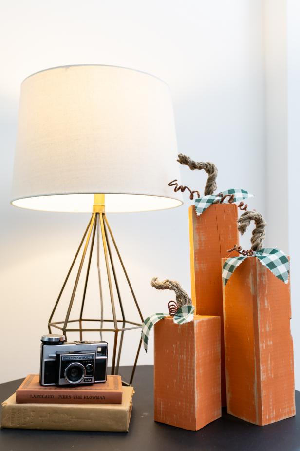 Three Wooden Pumpkins Sitting on a Side Table Beside Lamp