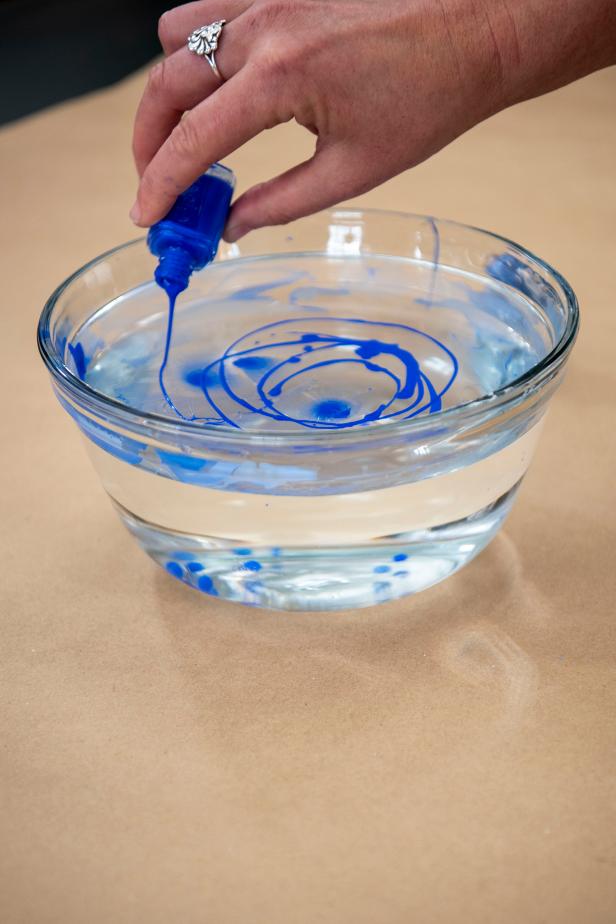 In a bowl of cold water, begin adding drops of fingernail polish. Next, pour the polish in a swirling pattern.