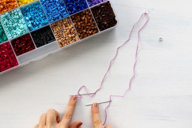 Cut a length of embroidery thread that is long enough to fit around your wrist at least twice. Tie a jump ring to the center of the string. Thread each end of the string through an embroidery needle.