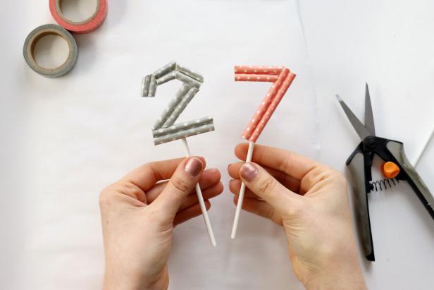 Put down parchment paper or any other non-stick surface. Use hot glue to glue all of the pieces together to form your number. Trim it as needed. Once the glue is dry, flip the number over and glue on a lollipop stick to finish.