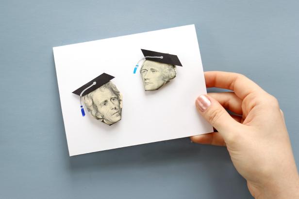 Next, cut graduation caps out of black paper and use small rolls of tape to attach them to the card on top of the money. Draw on tassels with metallic and colorful markers.