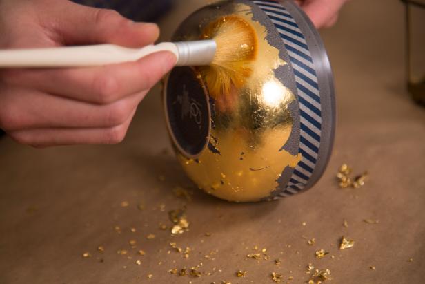 Lay sheets of gold leaf onto the adhesive, press and remove backing. For easier application, cut the sheets into smaller pieces. Brush off any excess with a soft paintbrush.