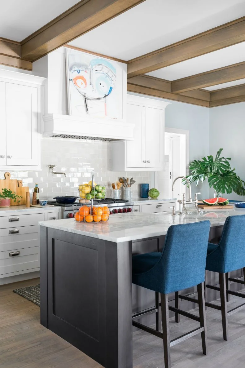 Although it may not be an obvious choice, art above a kitchen hood is an excellent way to bring a new vibe into the space with a simple swap out. This hood juts out 10 inches from the wall allowing it to also serve double duty as a shelf. The accessories and textiles in the space were all pulled from the colors seen in the painting by artist Sally King Benedict.