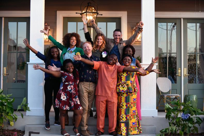 Host Jesse Tyler Ferguson and designers Breegan Jane, Carrie Locklyn, and Darren Keefe gleefully pose with a grateful Barobi family on the front porch of their new home