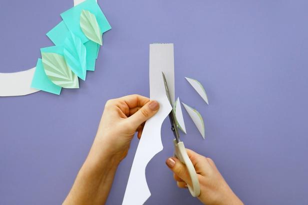Make additional leaves by scoring a line down a piece of cardstock. Fold it in half and cut half of a leaf shape down the fold. Open them up to reveal your leaves.