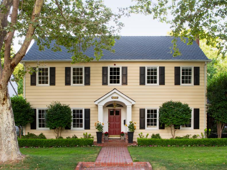 “Our 1931 Georgian Colonial looked kind of plain at first, though we loved the symmetry," say homeowners Janet and Jim Cassie of their 3,200 sq. ft. house. "We leaned into its traditional style by adding a portico, painting it yellow and replacing the louvered shutters with paneled ones.”

“We wanted our yard to play up the house’s formal look,” says Janet. The camellia trees were already there when she and Jim bought the home in 1998. They planted a neat row of boxwood with impatiens in front and hydrangeas in back, and put in an elegant brick path. A gable roof portico makes the home stately. Says Janet, “Our neighbors across the street told us that one reason they bought their house is because they love looking at it!”