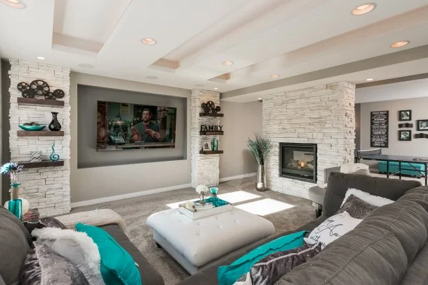 A stacked stone fireplace, a tray ceiling and bright color palette make this basement living area a family-friendly space made for relaxing. 