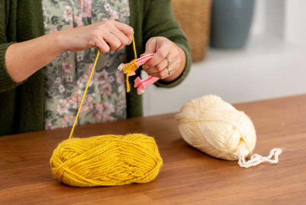 To make patterned, bi-color pom-poms you will need a pom-pom maker and two different colors of yarn skeins. Begin by wrapping one color on one side of the pom-pom maker.