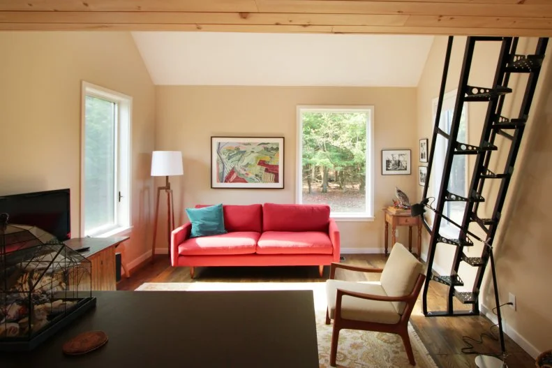 This Corning small house features three distinct buildings, a main house clad in corrugated weathered steel, a garage in black corrugated steel and a peaked barn in rough-sawn pine. A studio space in the home features a lofted bedroom above accessed by a modern metal staircase.