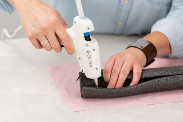 Using a lo-temp hot glue gun, wrap the fabric around the pipe insulation and glue to attach at the seam. Make sure to use a lo-temp hot glue as anything hotter will melt the foam.
