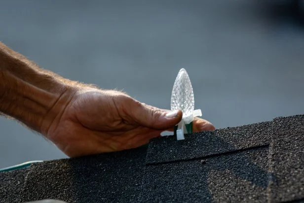 These handy clips are used to hold custom cut lengths of Christmas string lights in place on a roof. The clips hold the light bulbs themselves, creating a consistent line of lights across the roof of a house.