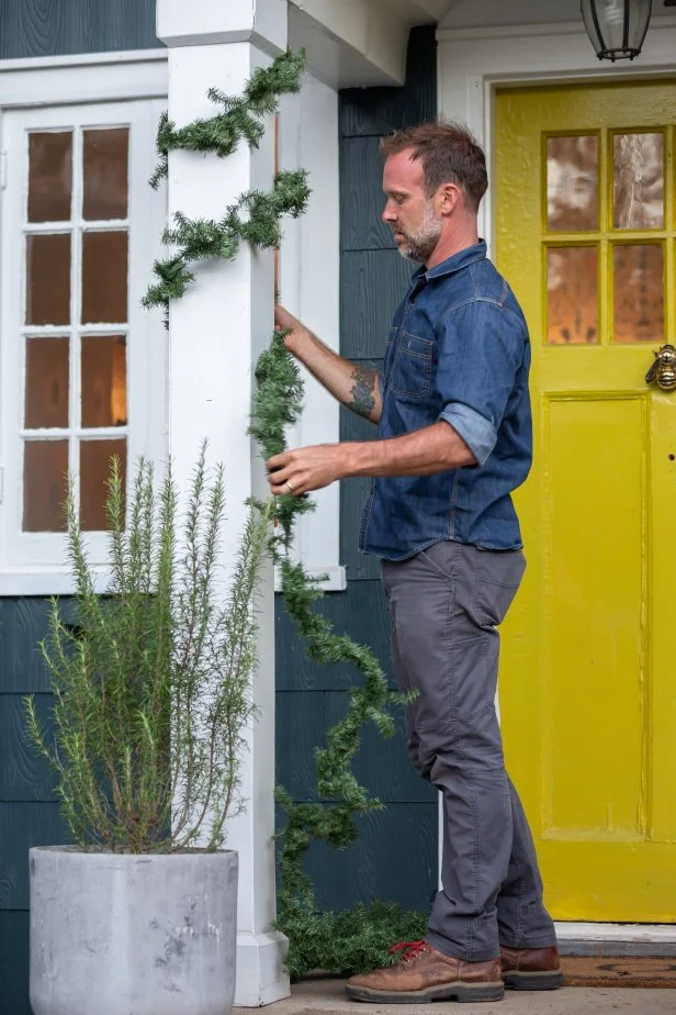 Greenery is wrapped around a porch post for a festive Christmas addition on the exterior of a home.