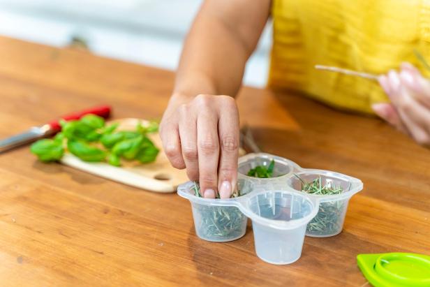 Woman Placing Herbs Into Container With Four Compartments