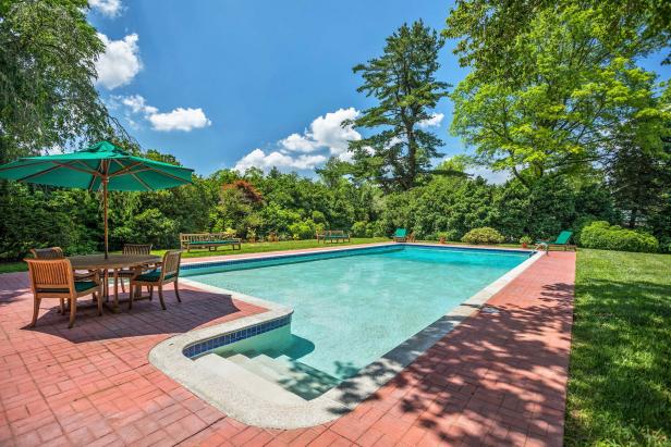 Large Pool With Brick Walkway and Outdoor Table With Umbrella