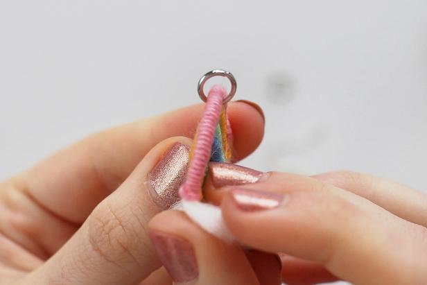 Use a thumbtack to poke a hole at the top of the rainbow. Use jewelry pliers to open up a jump ring, insert it through the hole, and close it up. Then use a second jump ring to attach that to the earring hook.