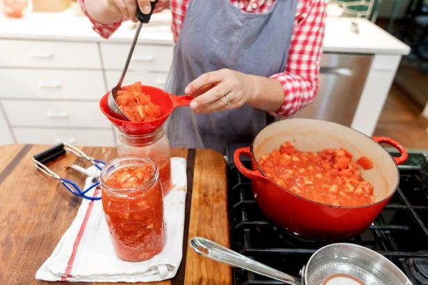 ladle tomatoes into canning jars