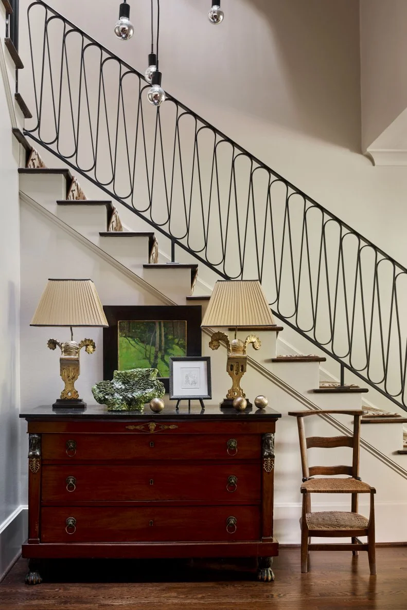 A contemporary foyer mixes fun antiques and a custom staircase.