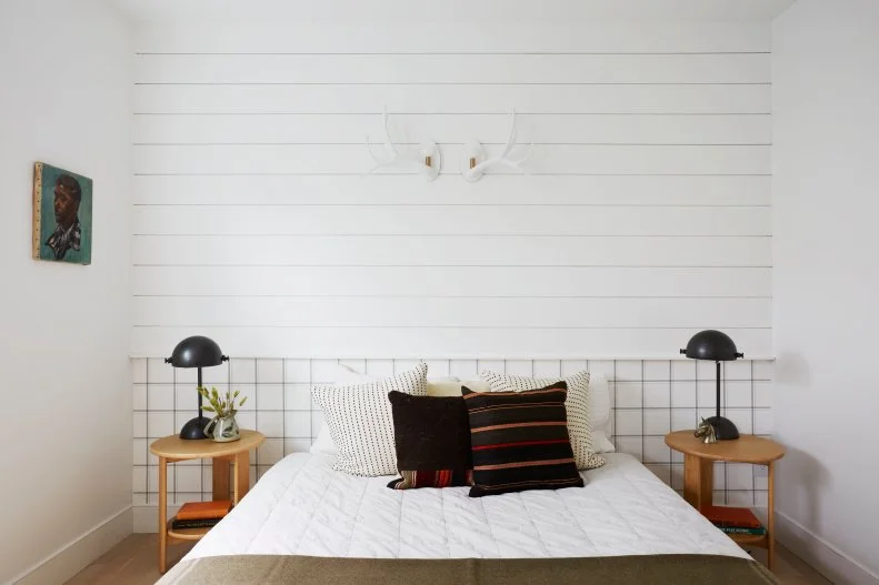 This guest bedroom includes white shiplap and antler sconces.