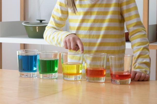 A child uses a glass harp made from barware and rainbow colored water.