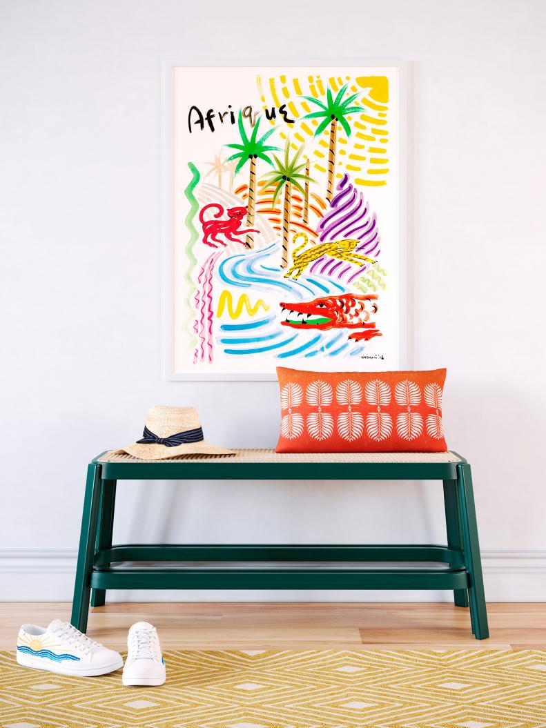 The sizable print (it’s 27 inches by 37 inches) in bright, cheerful hues makes a big impact — one and done. A dark green bench with a caned top nods to the imagery in the art. For extra vacation feels, there’s an orange pillow with palm fronds. 