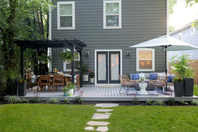 It's no secret that people love to perch and naturally gravitate toward spaces that invite them to sit and stay awhile. Make your patio or deck more appealing to the masses by first creating distinct and purposeful zones that pull people in, like a lounge, bar or outdoor kitchen + dining area. You can use a pergola, like the chic matte black one above, and a couple of rugs to break up the "open" floor plan and create the sense of two cozy rooms that your family will want to spend time in.